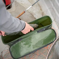 Angler putting fish into Wychwood Quick Drain Competitor Bass Bag on board boat